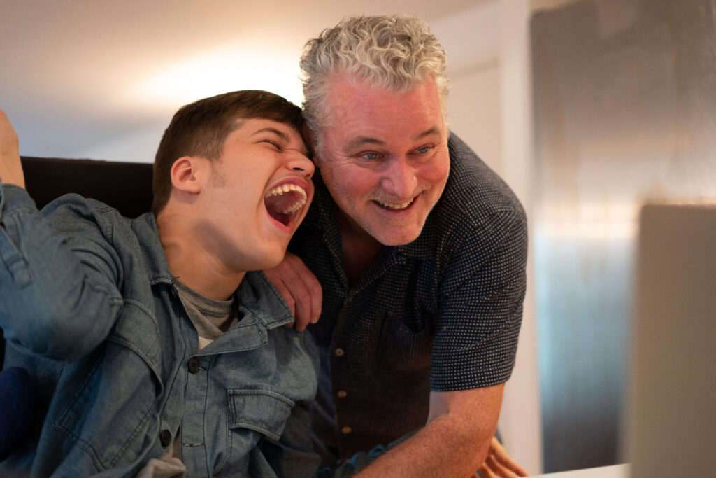 Father laughing with his son who is disabled.