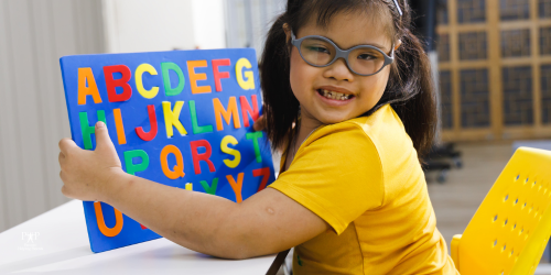 young girl with down syndrome holding an alphabet puzzle